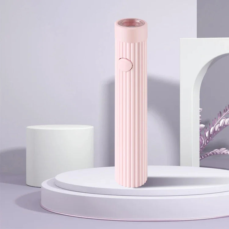 Pink ribbed electric hair curler standing on a white circular podium.